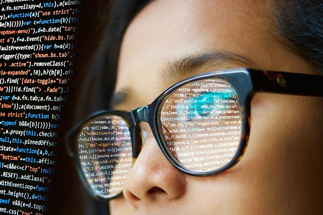 woman with glasses looking at a screen with code